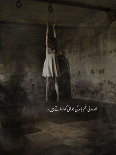 a woman hanging from a rope in an old building with arabic writing on the wall