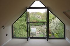 an open window in the corner of a room with trees and bushes behind it,