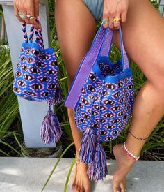 a woman's legs holding a blue and purple bag with tassels on it