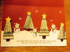 a christmas card with snowmen and trees on the front, sitting on a table