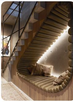 a curved staircase with pillows on it next to a wall mounted mirror in a living room