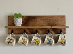 four coffee mugs are hanging on a wooden shelf