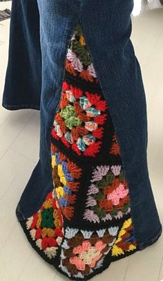 a person standing on the floor with their legs crossed wearing jeans and crocheted shoes