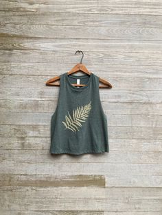 "this is my go to workout top as it pairs well with leggings for my yoga, barre or running workouts. i print my fern design in gold on this ultra cool green tank which has nice open armholes for venting all that sweat and to show off your arms! COLOR: evergreen S: chest 34\", length 19\" M: chest 36, length 20\" L: chest 38\", length 21\" XL: chest 40-42\", length 23\"" Cheap Vintage Tops For Outdoor, Summer Graphic Print Crop Top For Gym, Spring Graphic Print Crop Top For Workout, Spring Crew Neck Crop Top For Yoga, Spring Yoga Crop Top With Crew Neck, Spring Yoga Tank Top With Crew Neck, Green Crew Neck Workout Tank Top, Green Casual Crop Top For Yoga, Green Cropped Tank Top For Workout