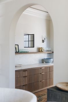 an arched doorway leads to a bathroom with marble countertops and wooden cabinets, along with a sink