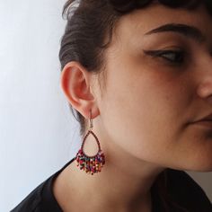 These earrings are composed of burgundy and multicolored (burgundy, red, orange, yellow, purple, turquoise...) seed beads that are sewn around a teardrop steel base by means of silk thread. Steel hook with silicone stoppers. Red Teardrop Earrings With Dangling Beads, Multicolor Teardrop Beaded Earrings With Tiny Beads, Red Teardrop Beaded Earrings With Dangling Beads, Red Teardrop Beaded Dangling Earrings, Multicolor Beaded Teardrop Earrings, Handmade Multicolor Teardrop Earrings, Multicolor Teardrop Beaded Earrings, Handmade Multicolor Teardrop Earrings For Parties, Purple Teardrop Beaded Earrings