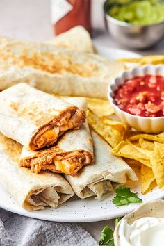 two burritos on a plate with salsa and tortilla chips next to it