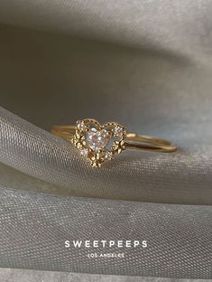 a heart shaped diamond ring sitting on top of a white satin material bag with the words sweet peps written below it