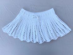 a white crochet skirt hanging on a wall with the bottom part of it pulled up