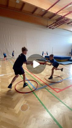 two young boys are playing frisbee in an indoor gym with colored lines on the floor