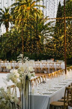 the tables are set up with white flowers and greenery in vases on them