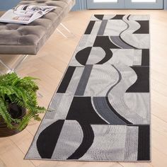 a modern rug in the middle of a living room with a couch and potted plant