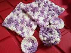 a purple and white crocheted mitt sitting on top of a red surface