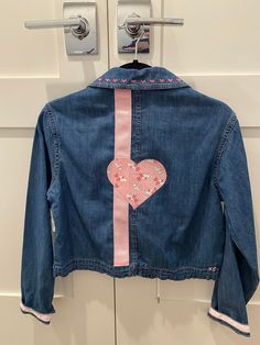 a denim jacket with a pink heart on it