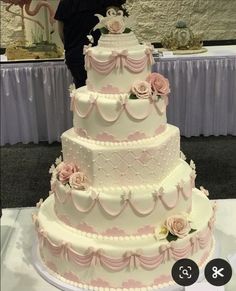 a three tiered wedding cake with pink flowers on top and white icing around the edges