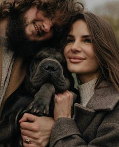 a man and woman holding a dog in their arms