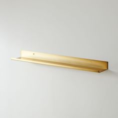 a gold shelf mounted to the side of a wall