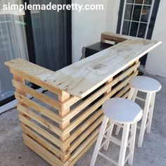 an outdoor bar made out of pallets and wooden planks with three stools