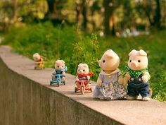 there are many small teddy bears sitting on the edge of a wall and one is riding a toy car