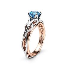 an engagement ring with a blue topazte stone in rose gold and white gold