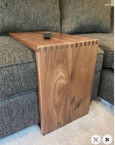 a wooden table sitting on top of a couch next to a gray couch with a remote control