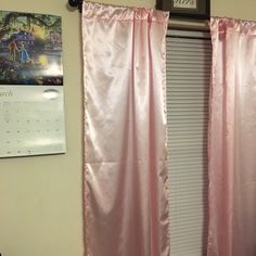 a window with pink curtains and a calendar on the wall