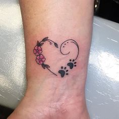 a small heart shaped tattoo with paw prints and flowers on the side of the foot