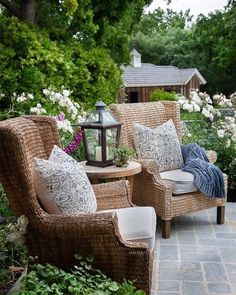 an instagram with two wicker chairs and pillows on the back patio, surrounded by white flowers