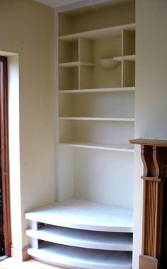 an empty room with some shelves and a fire place