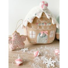 a gingerbread house ornament with snowflakes on the ground next to it