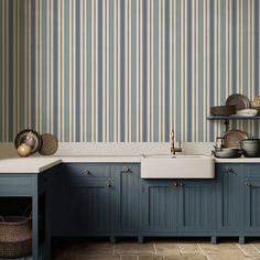 a kitchen with blue cabinets and striped wallpaper on the walls, along with a white sink