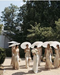 a group of bridesmaids walking down a path with umbrellas over their heads