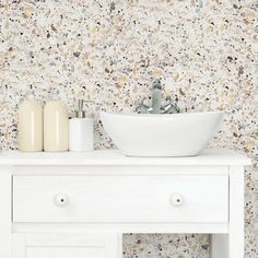 a white sink sitting on top of a wooden counter next to a wallpapered wall