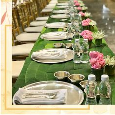 a long table is set with silverware and pink flowers in vases on it