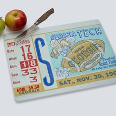 two apples and a ticket for the georgia tech football game are on display next to a knife