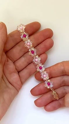 two hands holding a bracelet with pink and white stones