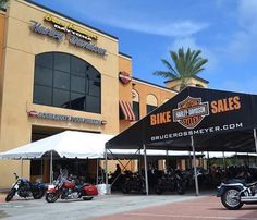 motorcycles are parked in front of a motorcycle sales building on the side of the road