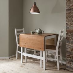 a wooden table with two white chairs and a light hanging from the ceiling over it