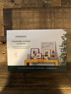 an advertisement for the framebridge christmas tree is displayed on a wooden table in front of a wood paneled wall