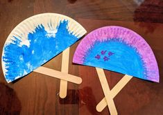 two paper plates with blue and purple designs on them sitting on a wooden table next to each other