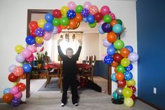 an arch made out of balloons is in the middle of a room with a table and chairs