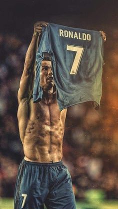 a shirtless man holding up a blue jersey