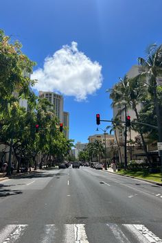 an empty street with palm trees and buildings in the background