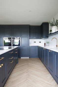 a large kitchen with blue cabinets and white counter tops, gold pulls on the handles