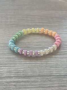 the multicolored beaded bracelet is displayed on a wooden table