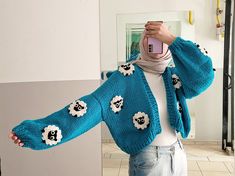 a woman taking a selfie in front of a mirror wearing a blue sweater with sheep on it