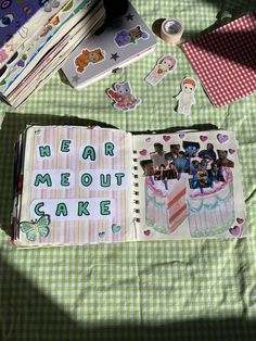 an open notebook with pictures and stickers on it next to other items that include cake