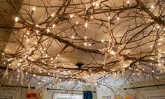 a bedroom with lights hanging from the ceiling and branches on the ceiling over the bed