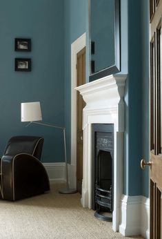 a living room with blue walls and white trim on the fireplace mantel, along with a black leather chair