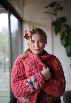 a woman wearing a red sweater and flower in her hair is posing for the camera